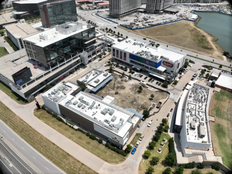 Aerial view of a modern commercial complex with several buildings, parking lots, and nearby roads.