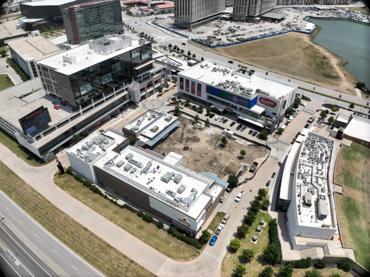 Aerial view of a modern commercial complex with several buildings, parking lots, and nearby roads.