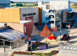 A shopping center with The Pavilion sign and holiday decorations, including a large ornament and red trees.